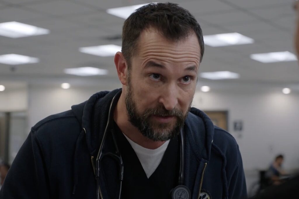 Onde assistir às séries vencedoras do Emmy 2025 1 O Dr. Ed Costas (Milo Ventimiglia) aparece em um hospital, usando estetoscópio no pescoço, na série The Pitt, da HBO Max.