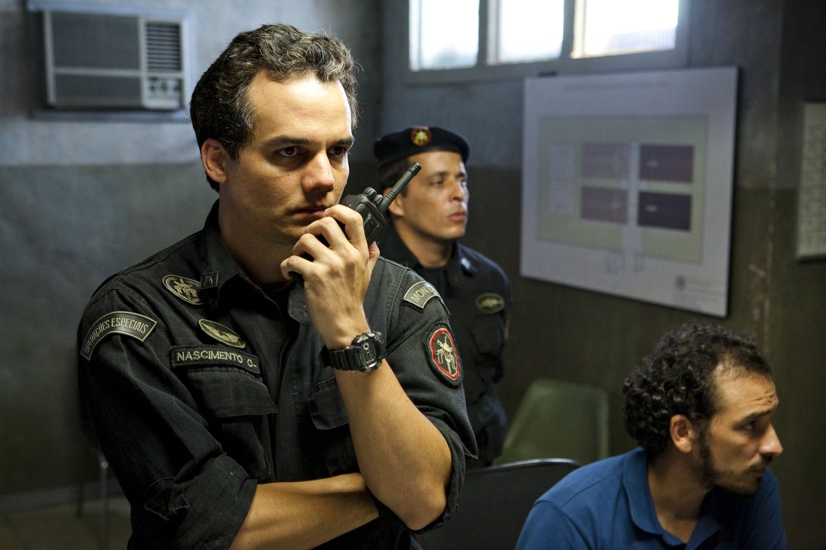Wagner Moura como Coronel Nascimento, em uniforme do BOPE, fala em um rádio comunicador dentro de uma sala de operações. Cena do filme Tropa de Elite 2: O Inimigo Agora é Outro (2010).