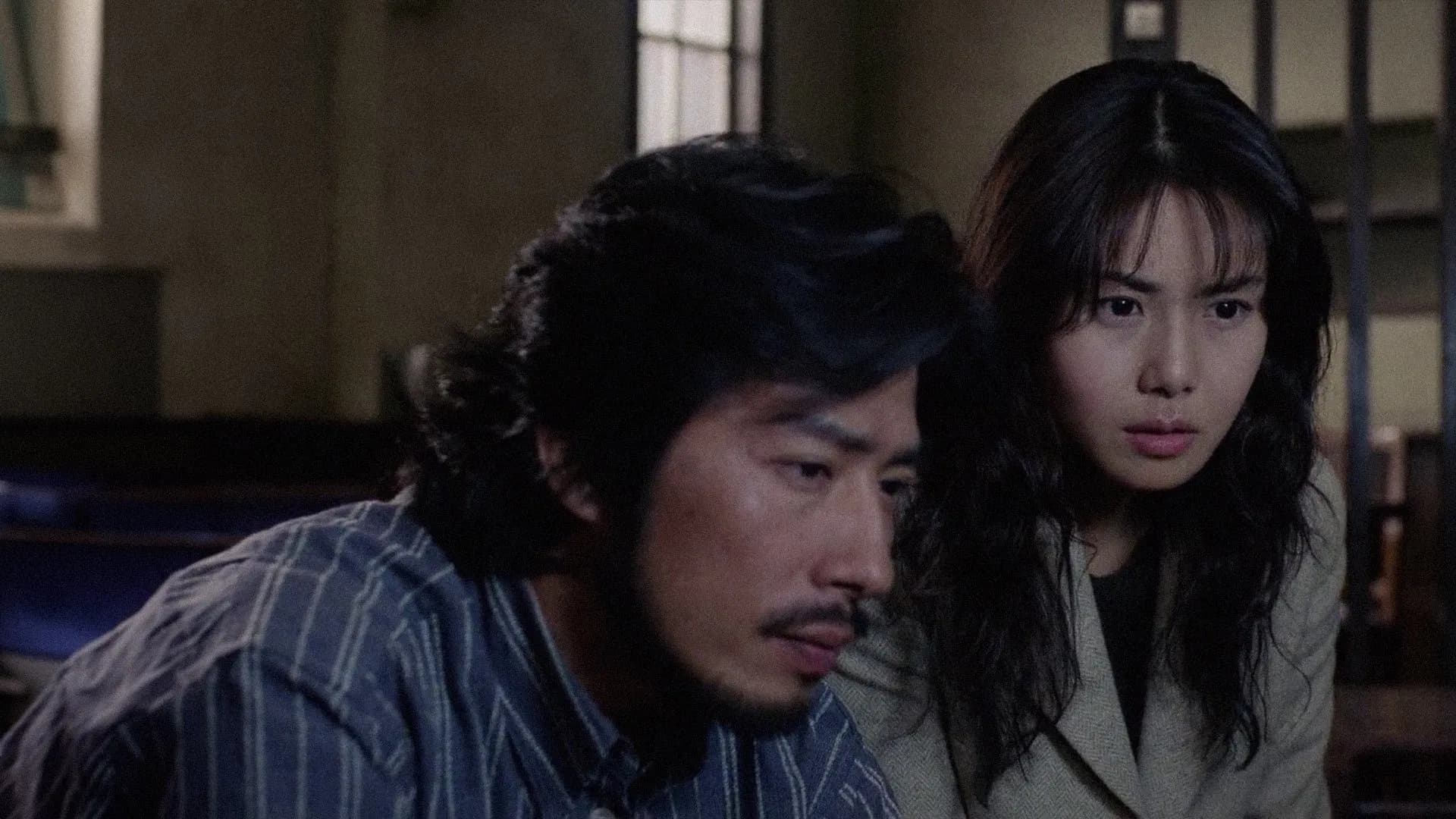 Filmes de terror asiáticos famosos: 12 obras que conquistaram o mundo 2 homem e mulher observam algo com expressão tensa em ambiente fechado e pouco iluminado.