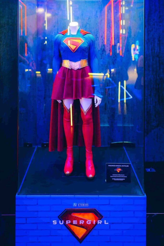 Uniforme original de Supergirl exposto em vitrine iluminada na CCXP25.