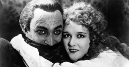 Conrad Veidt como Gwynplaine em O Homem que Ri (1928), com expressão marcada pelo sorriso permanente ao lado de personagem feminina